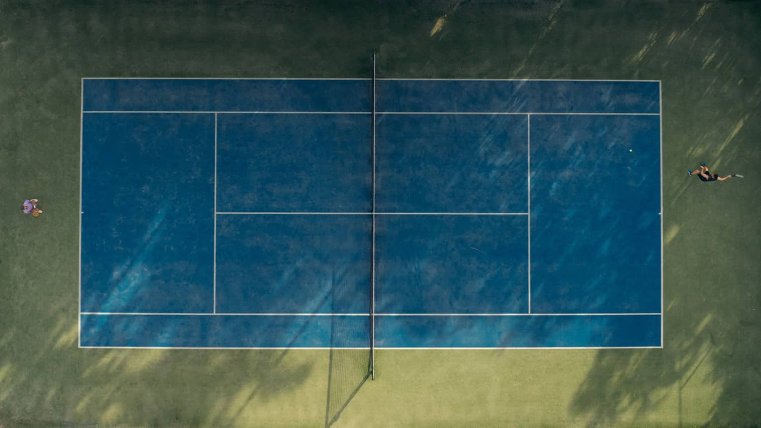 Aerial image of two people playing tennis on a tennis court.