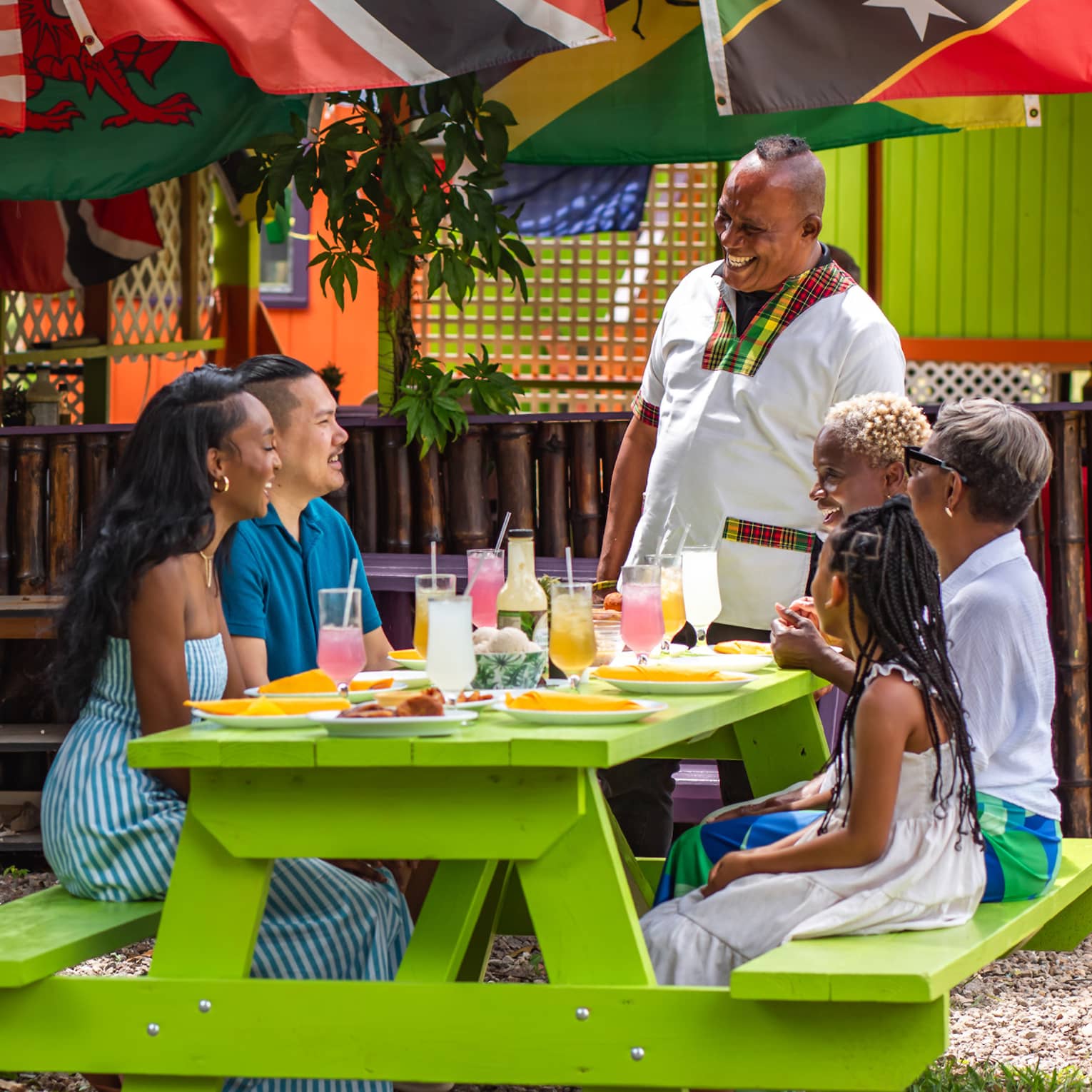 Guests sitting at a picnic table outside under a large tree