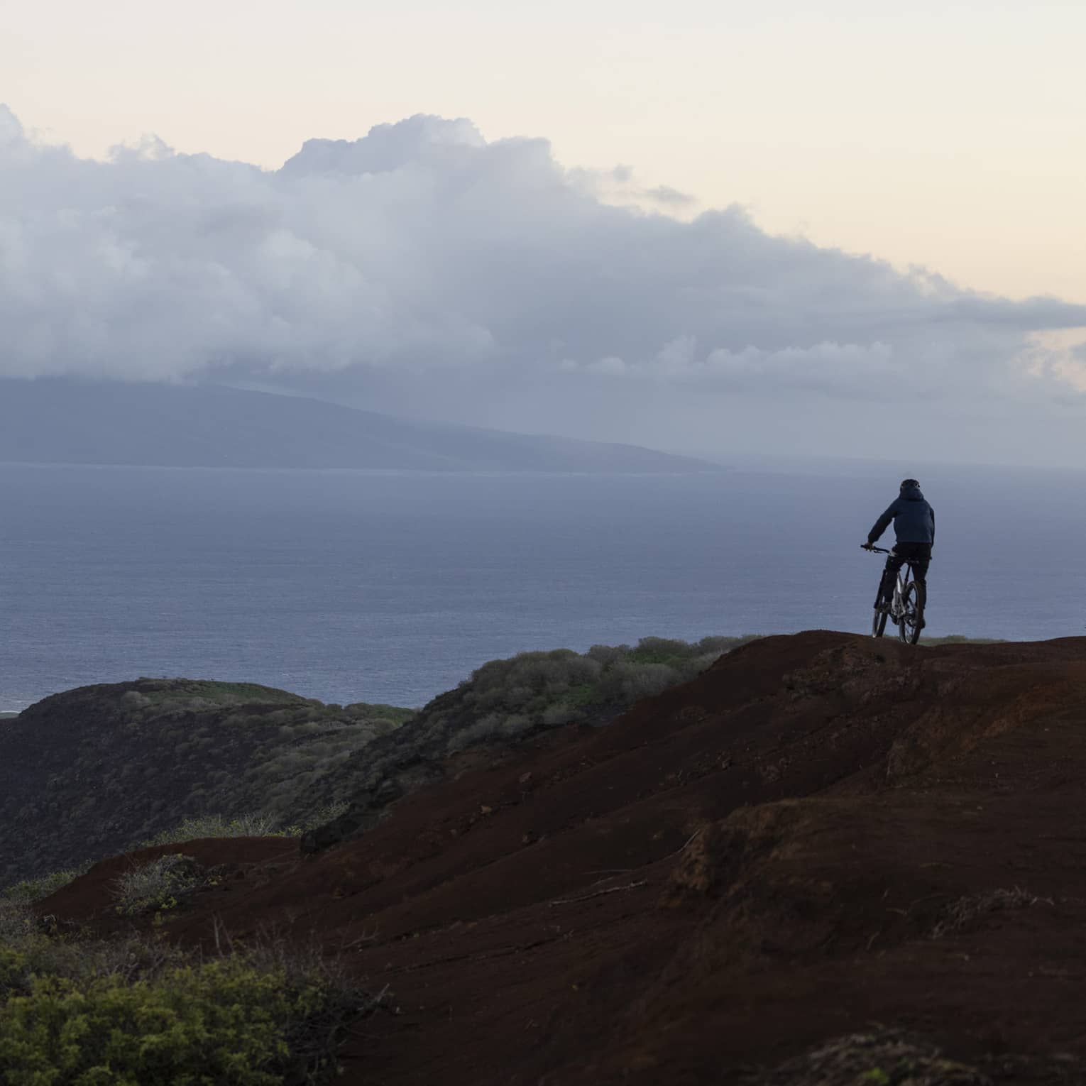 A person rides mountain bike on rugged, tropical terrain