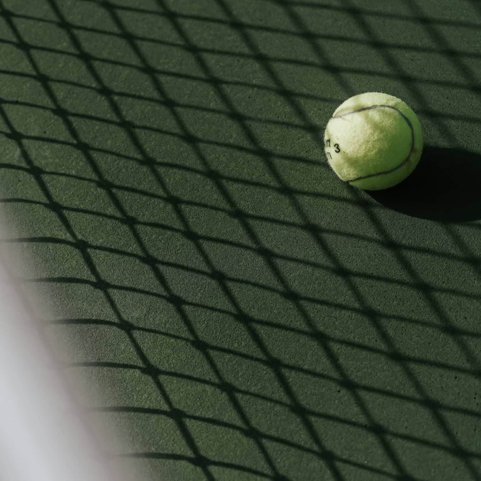 Tennis ball on tennis court with shadow of net