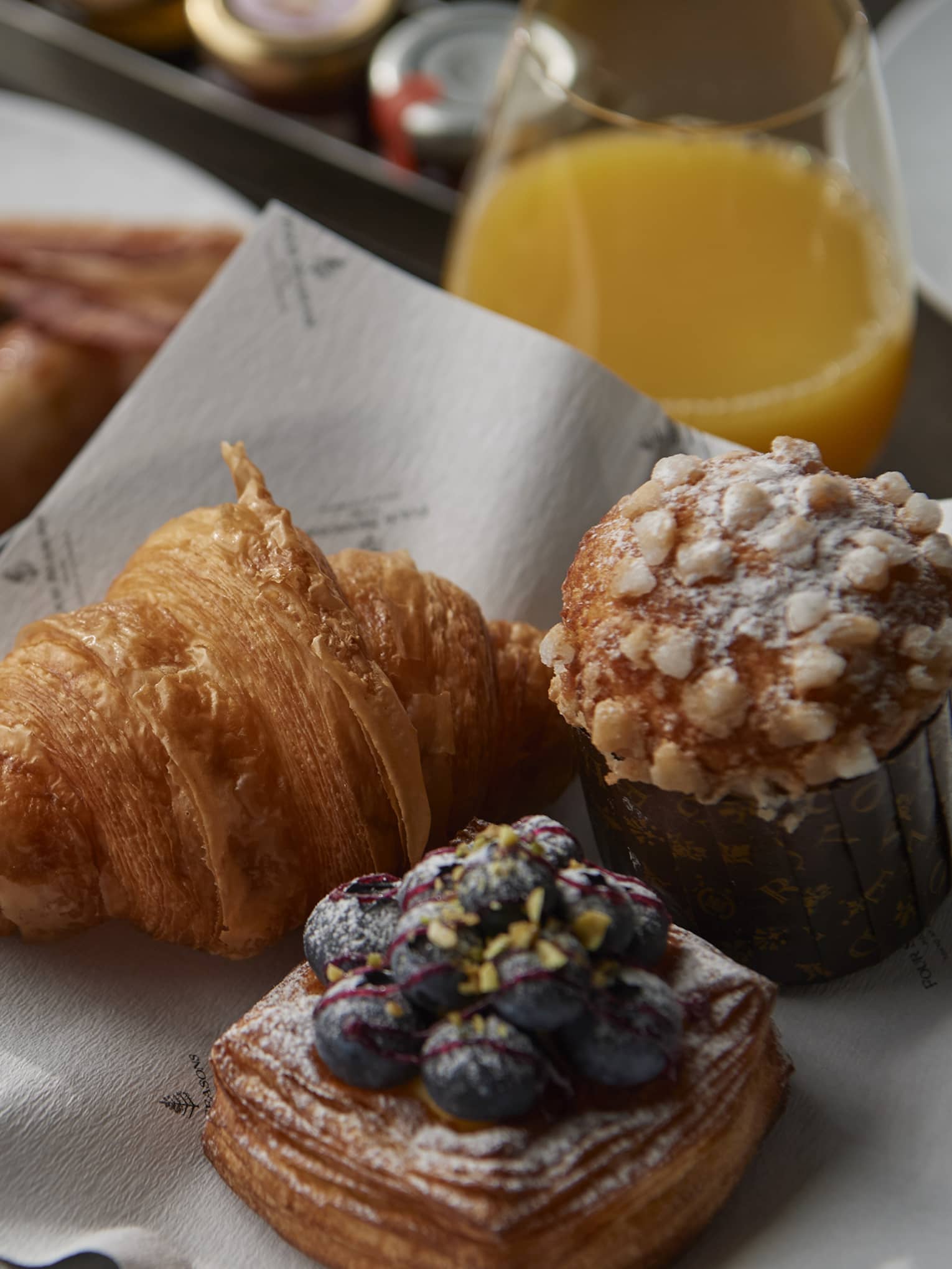 In-room dining breakfast spread with bakery items and orange juice