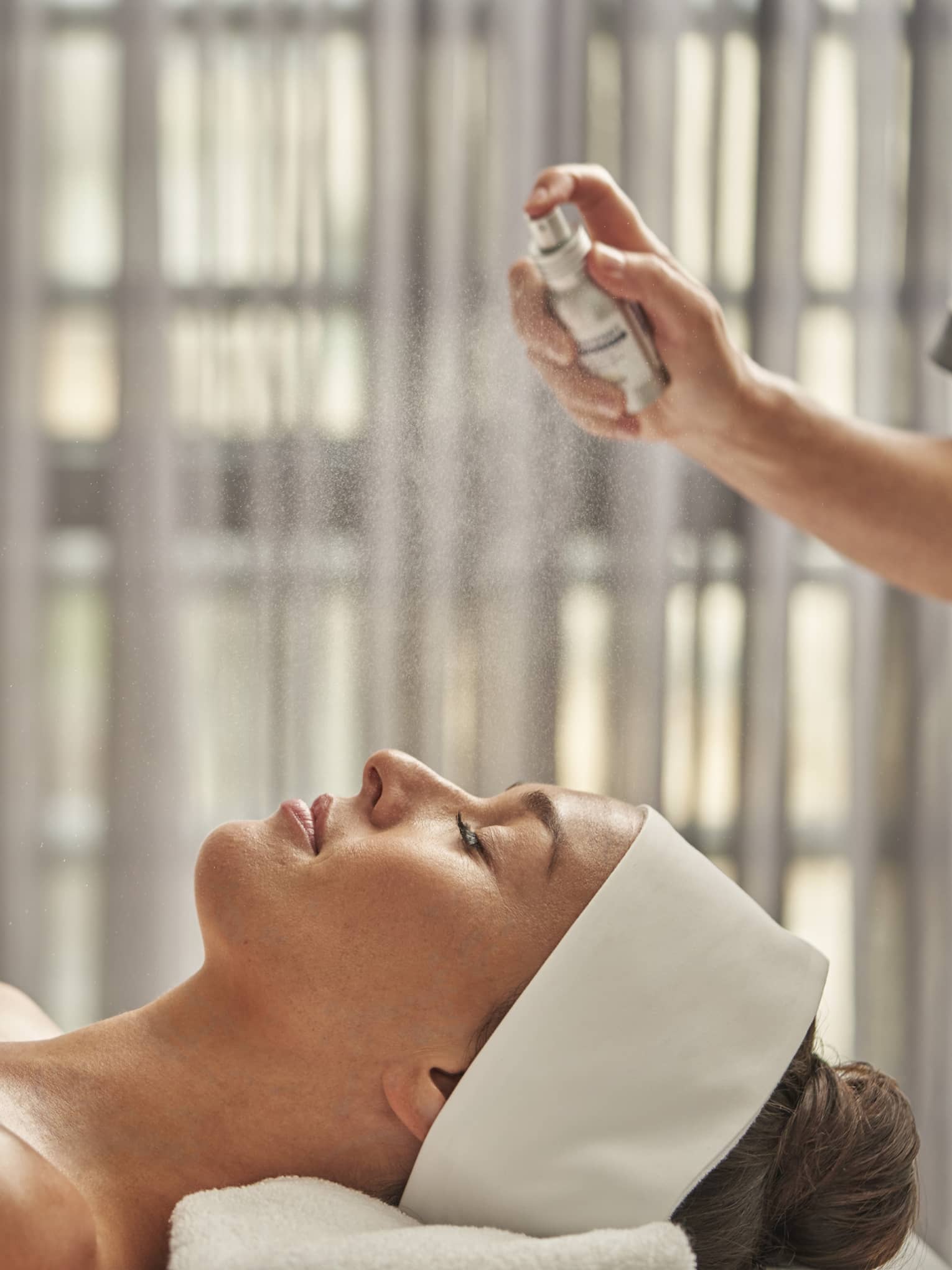 A woman being sprayed with mist during a spa treatment.