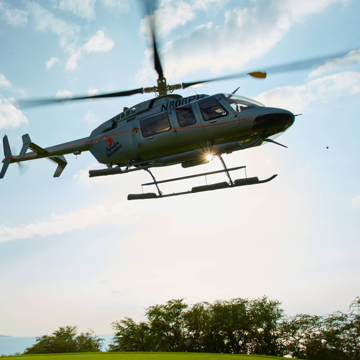 Helicopter hovers over green lawn under blue sky