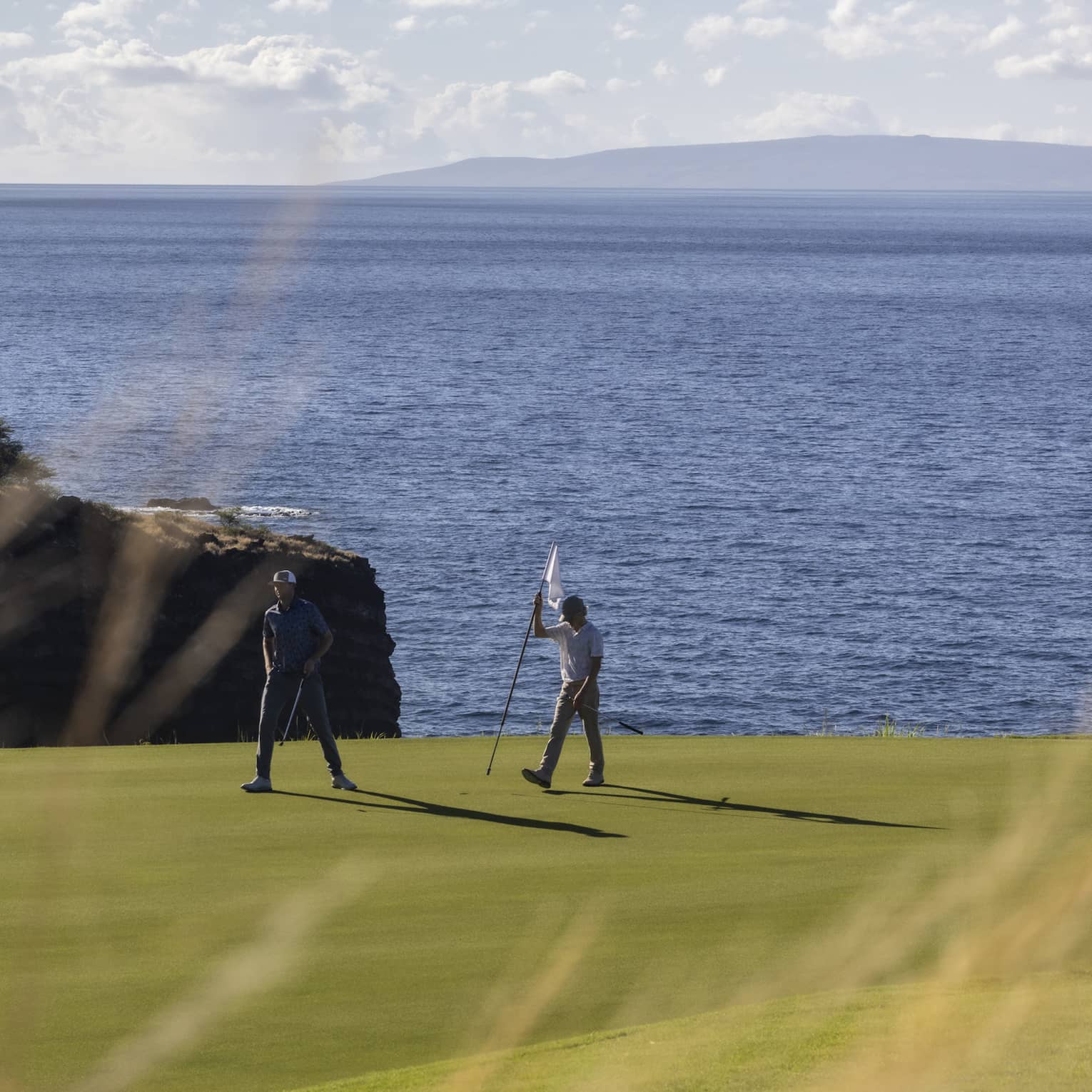 Two golfers on oceanside green at Four Seasons Resort Lanai