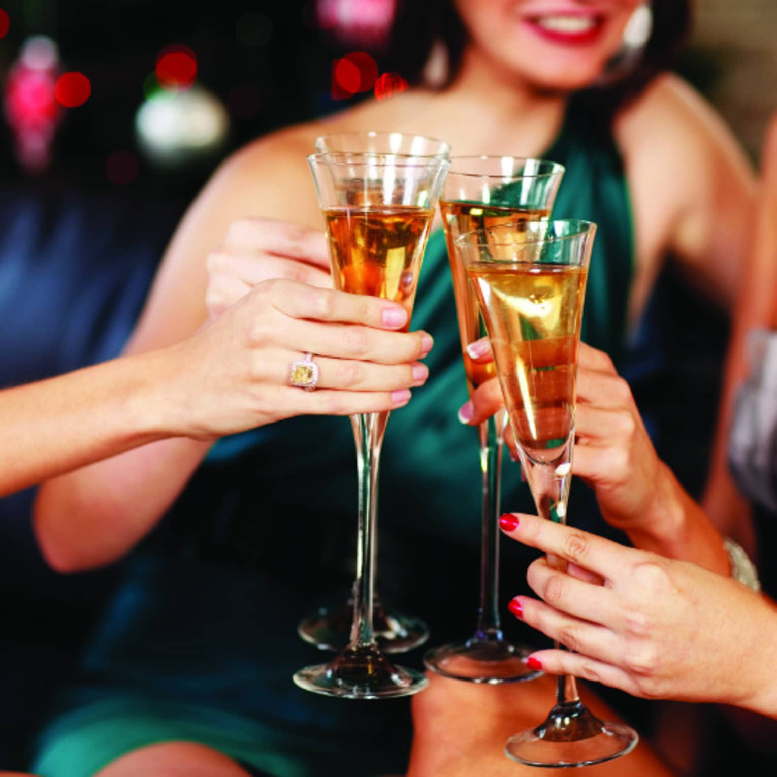 Close-up of women in evening gowns toasting with glasses of Champagne