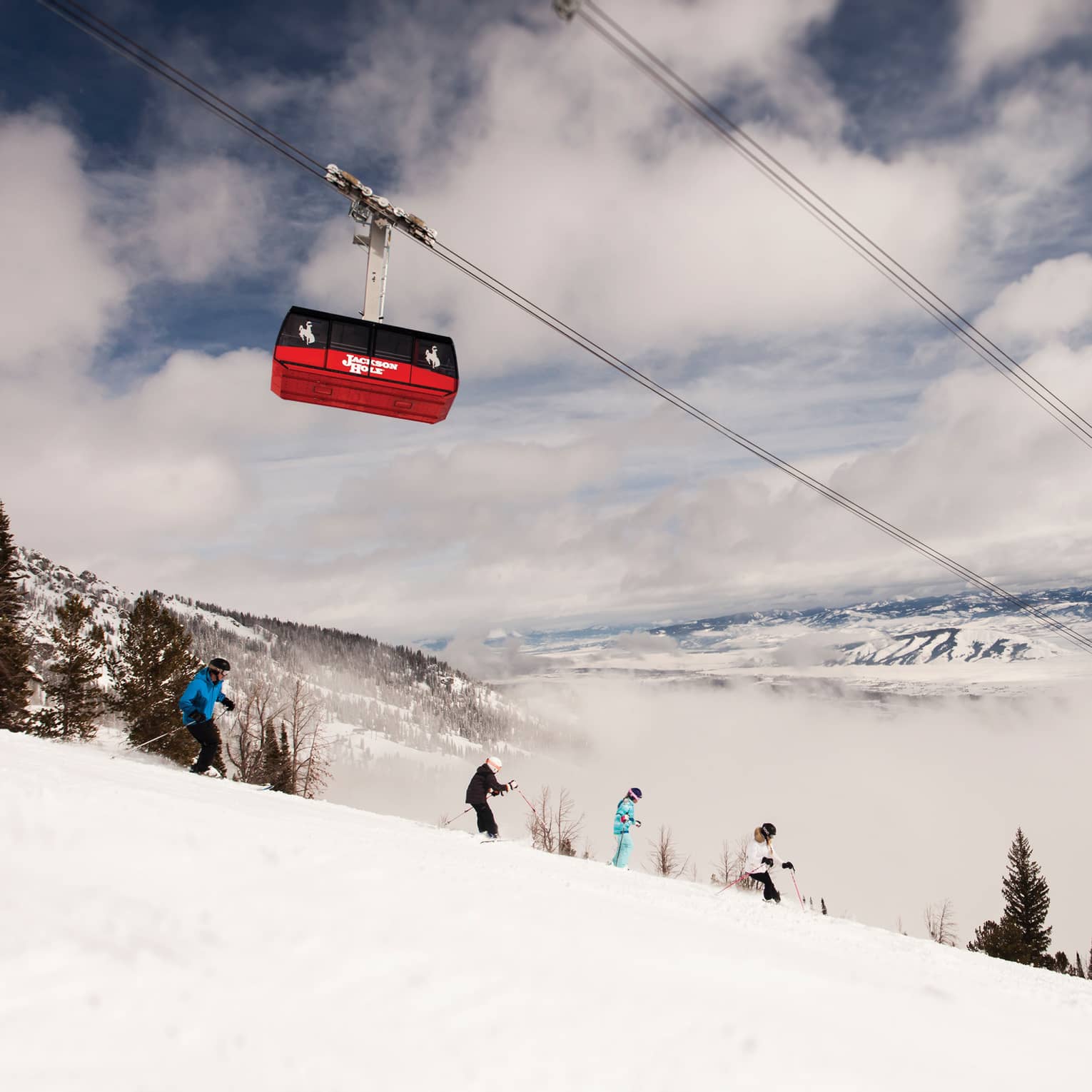 Red Sweetwater Gondola ski lift on wire above hikers on snowy mountain