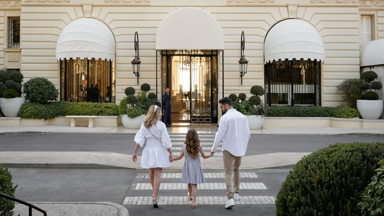 Family of three holding hands while walking toward the Grand-H�tel