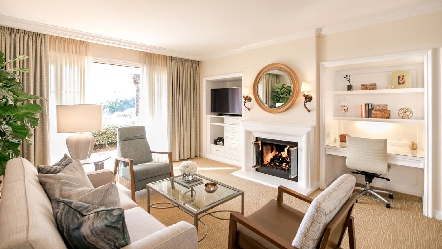 Sunny, modern villa seating room with white fireplace under round mirror, by built-in desk