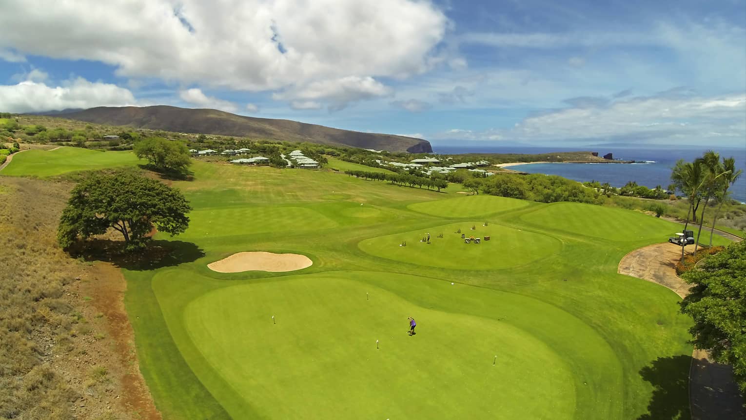 View over sweeping green golf course under blue sky with clouds 