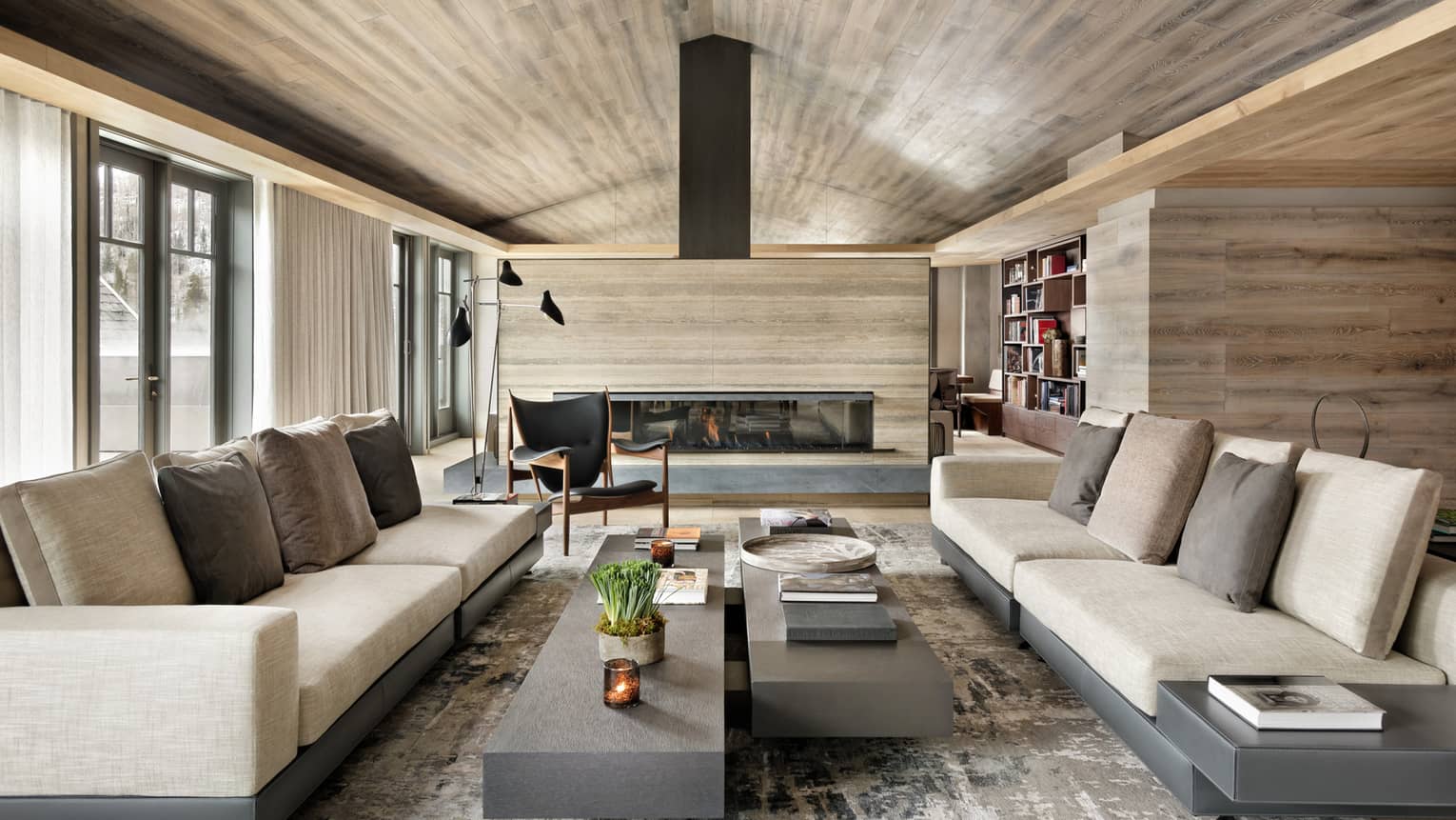 Long linen sofas, slate coffee tables under modern light wood ceiling, fireplace