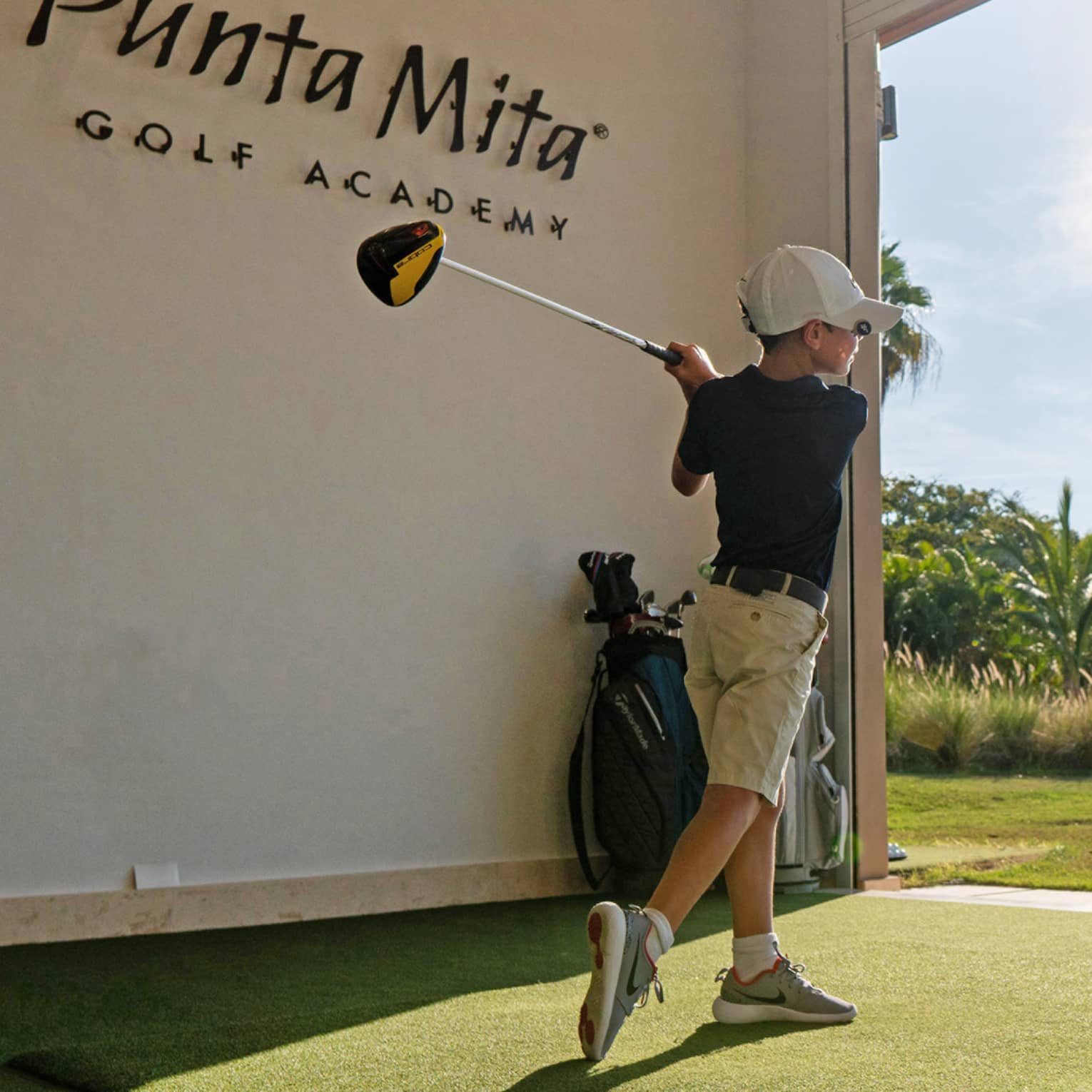 A young child practicing golf in a driving range.