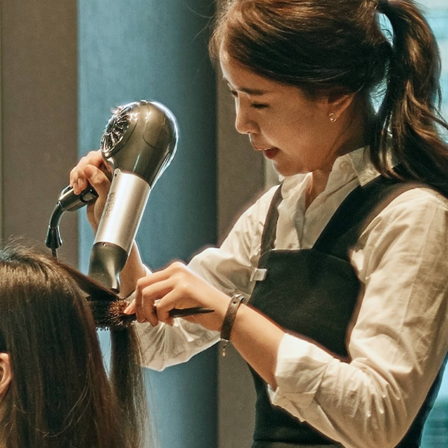 Hair stylist blow dries woman's hair in hotel salon