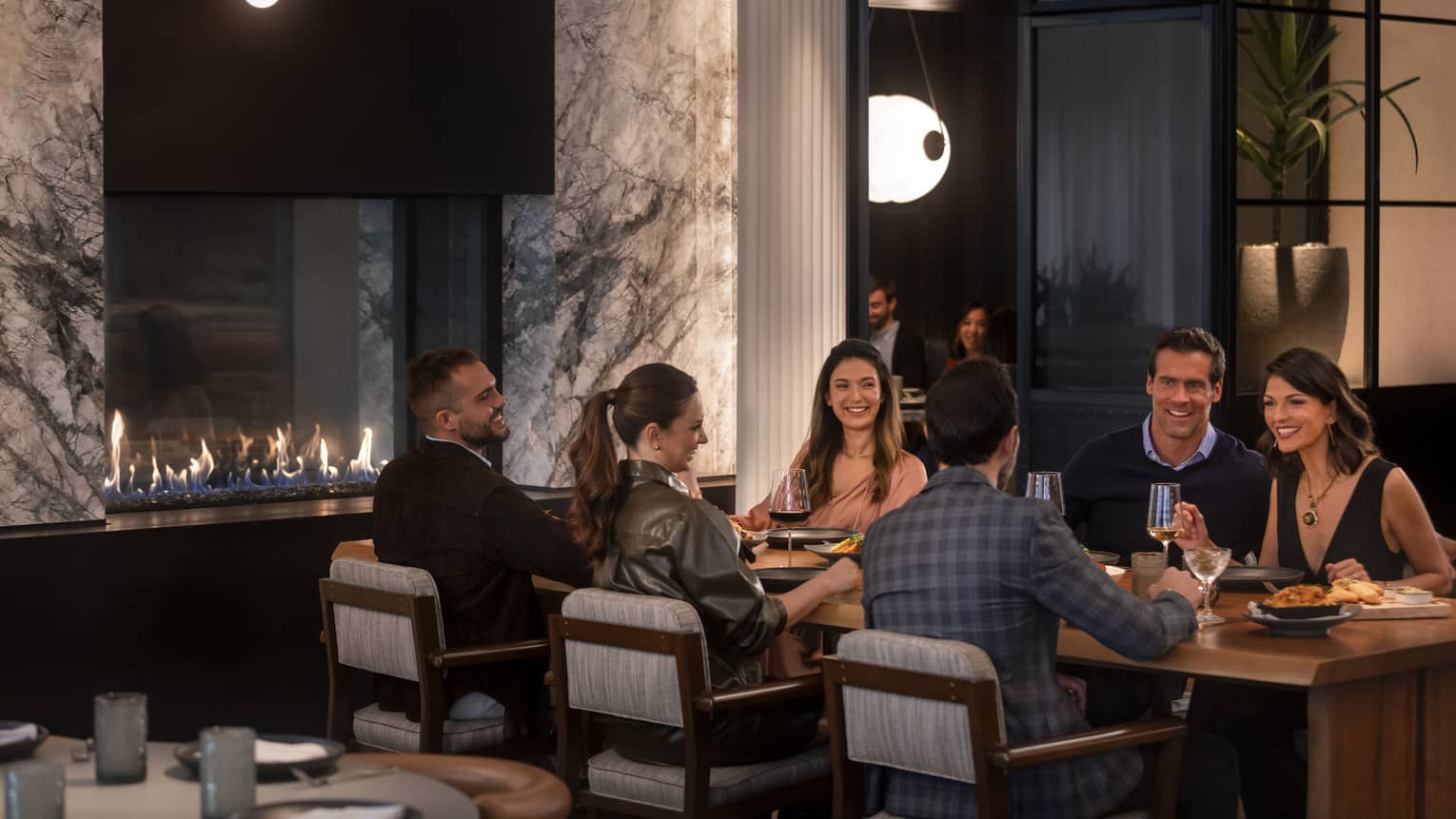 A group of people sitting at a large table in a dimly lit restuarant.