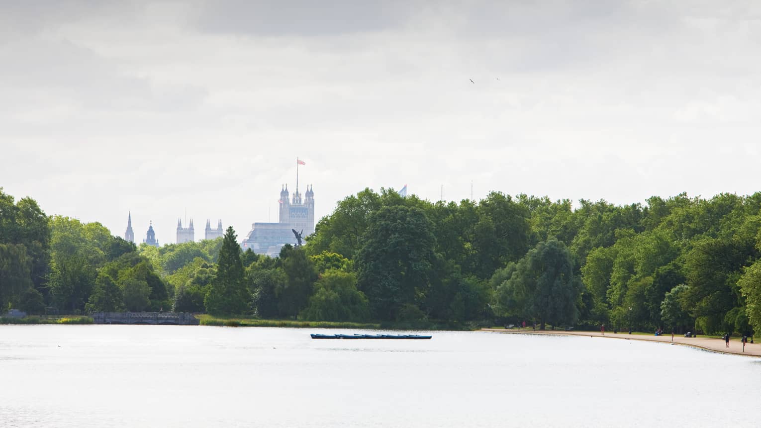Tops of buildings in London visible over the tops of trees and across the lake