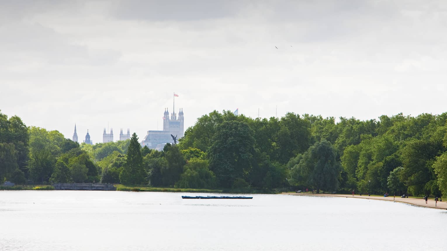 Tops of buildings in London visible over the tops of trees and across the lake