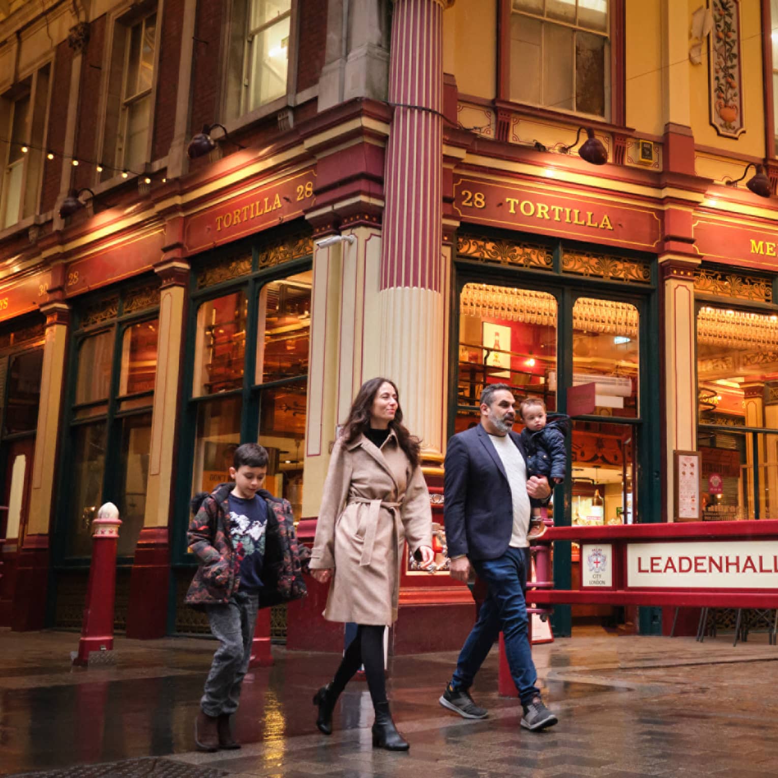 A family walks through London city street at night