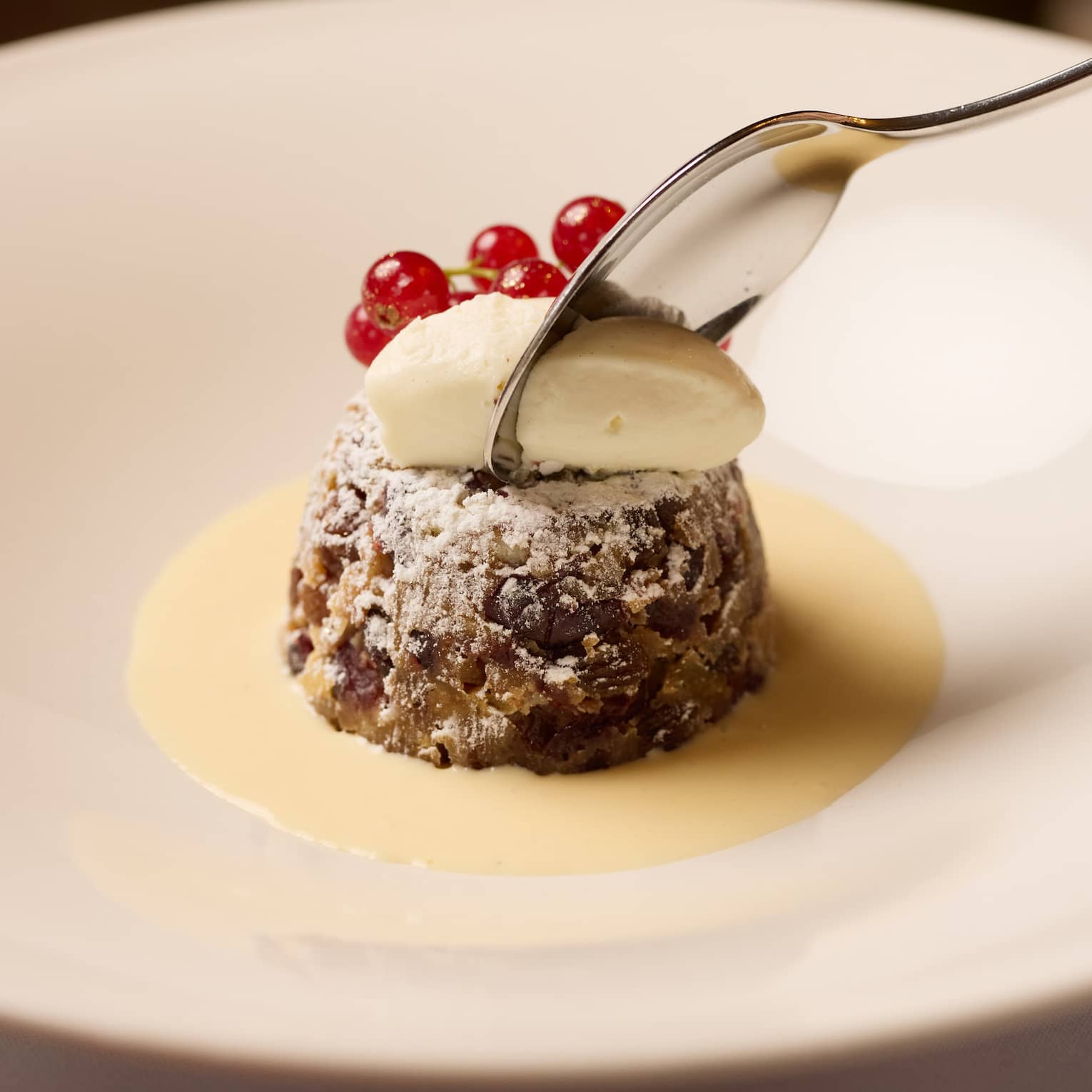 A shallow round bowl holds a desert item with a sauce and garnishes.