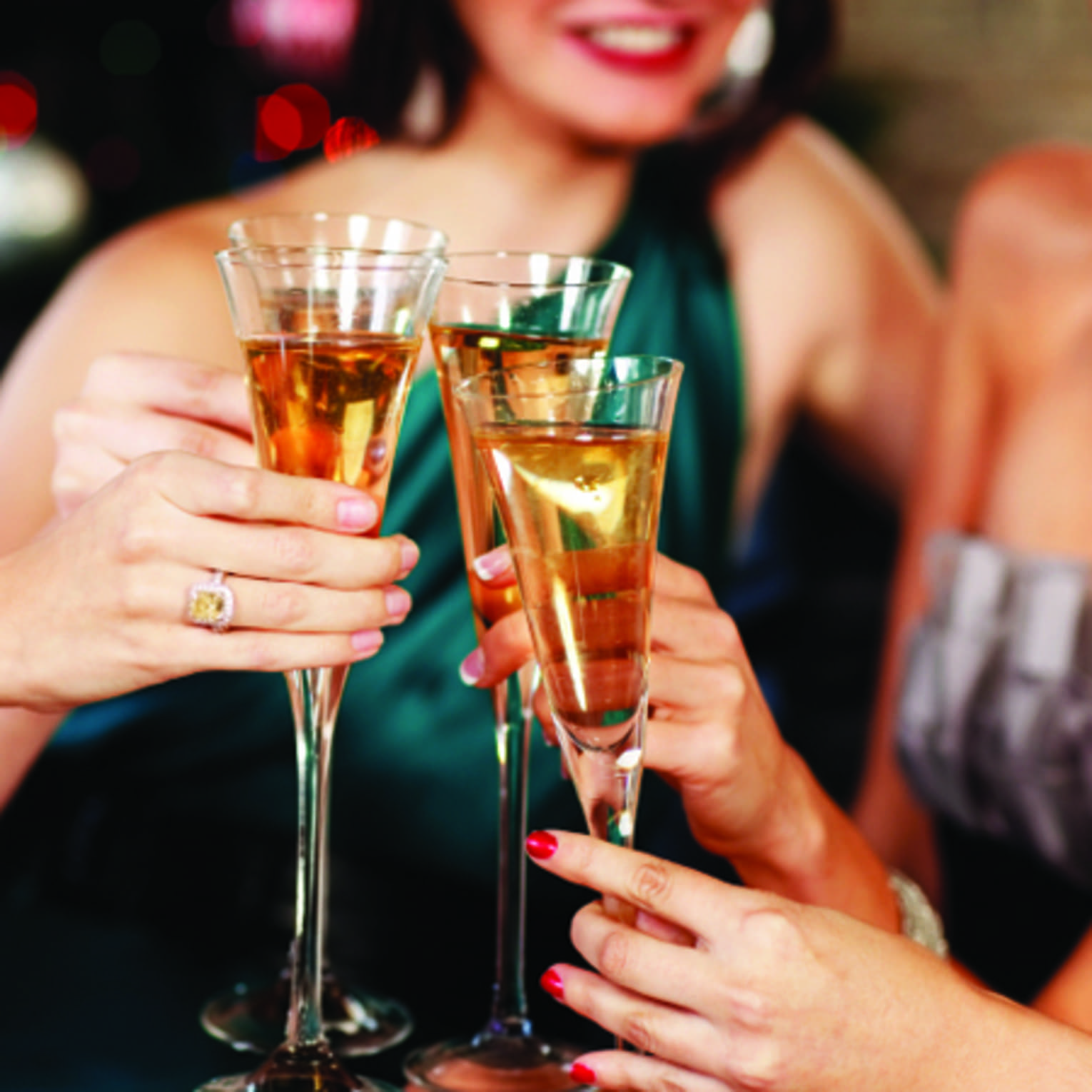 Close-up of women in evening gowns toasting with glasses of Champagne
