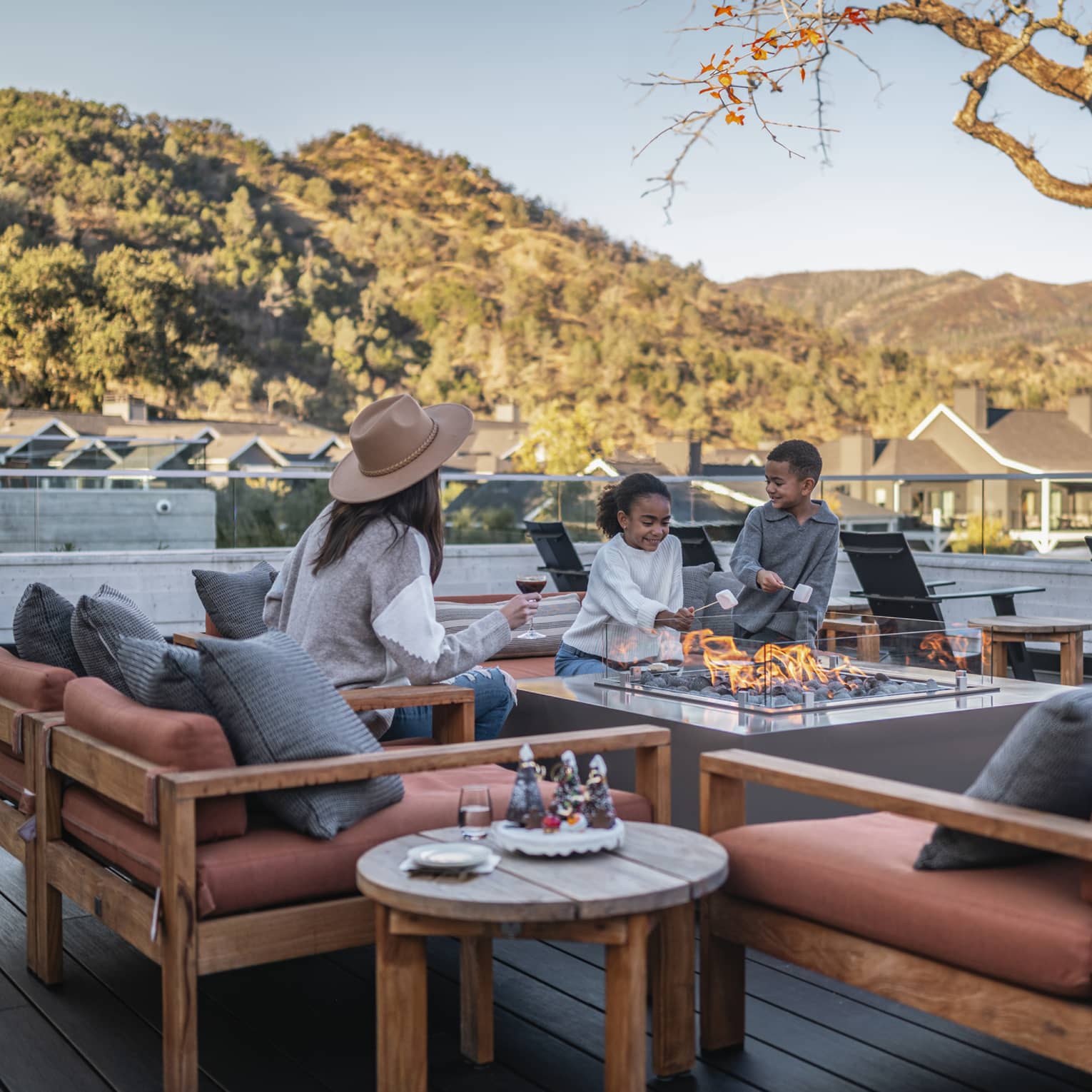 Three guests roasting marshmallows on an outdoor terrace.