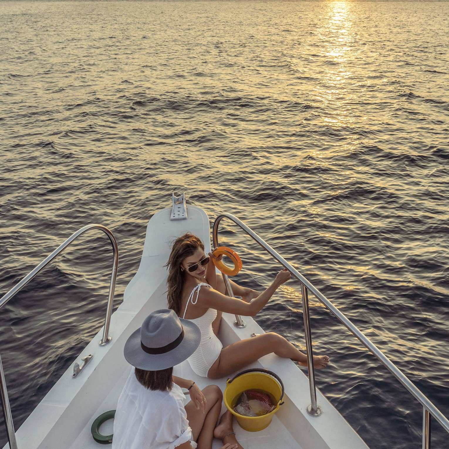 Two women enjoy snacks at the helm of a private yacht at sunset