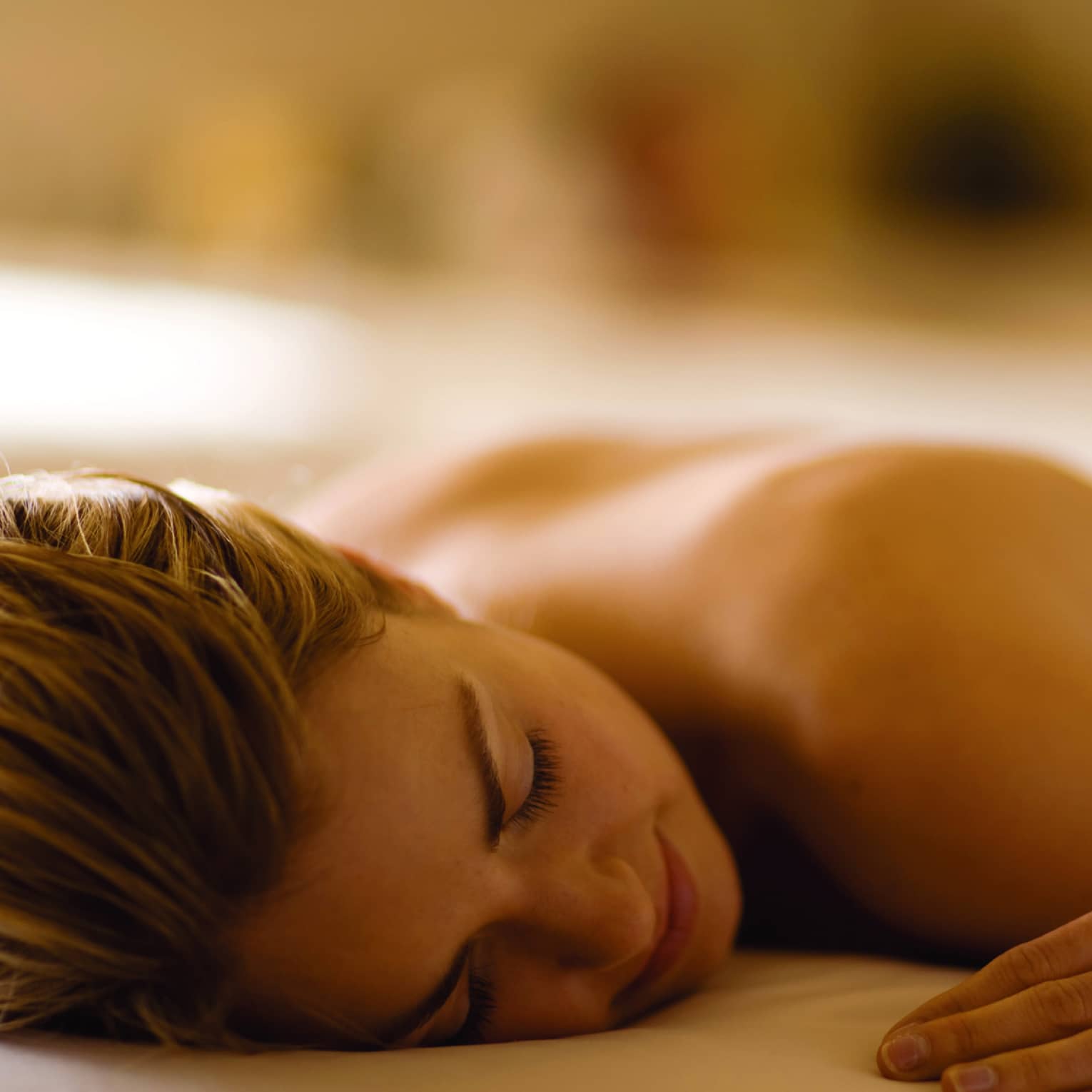 Woman lays with eyes closed, face-down on massage table