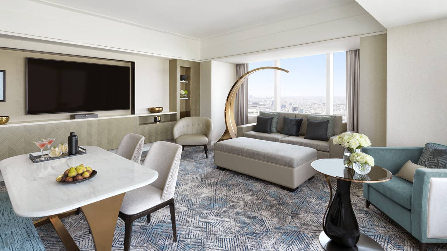 Living area with sofa, two arm chairs, TV and dining table for four