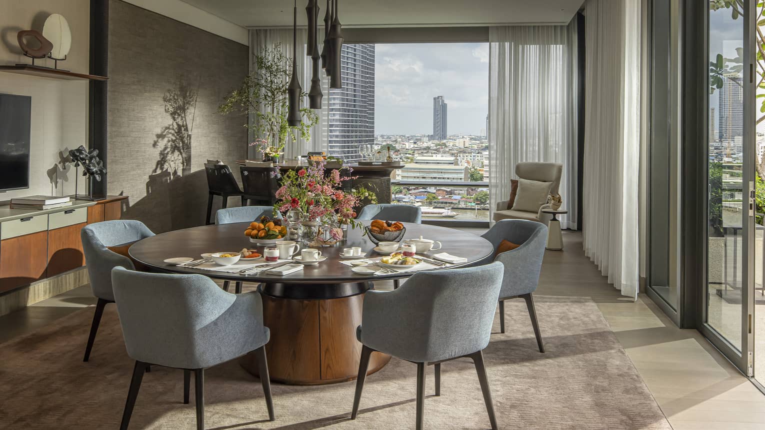 Hotel suite with large round dining table and views of Bangkok