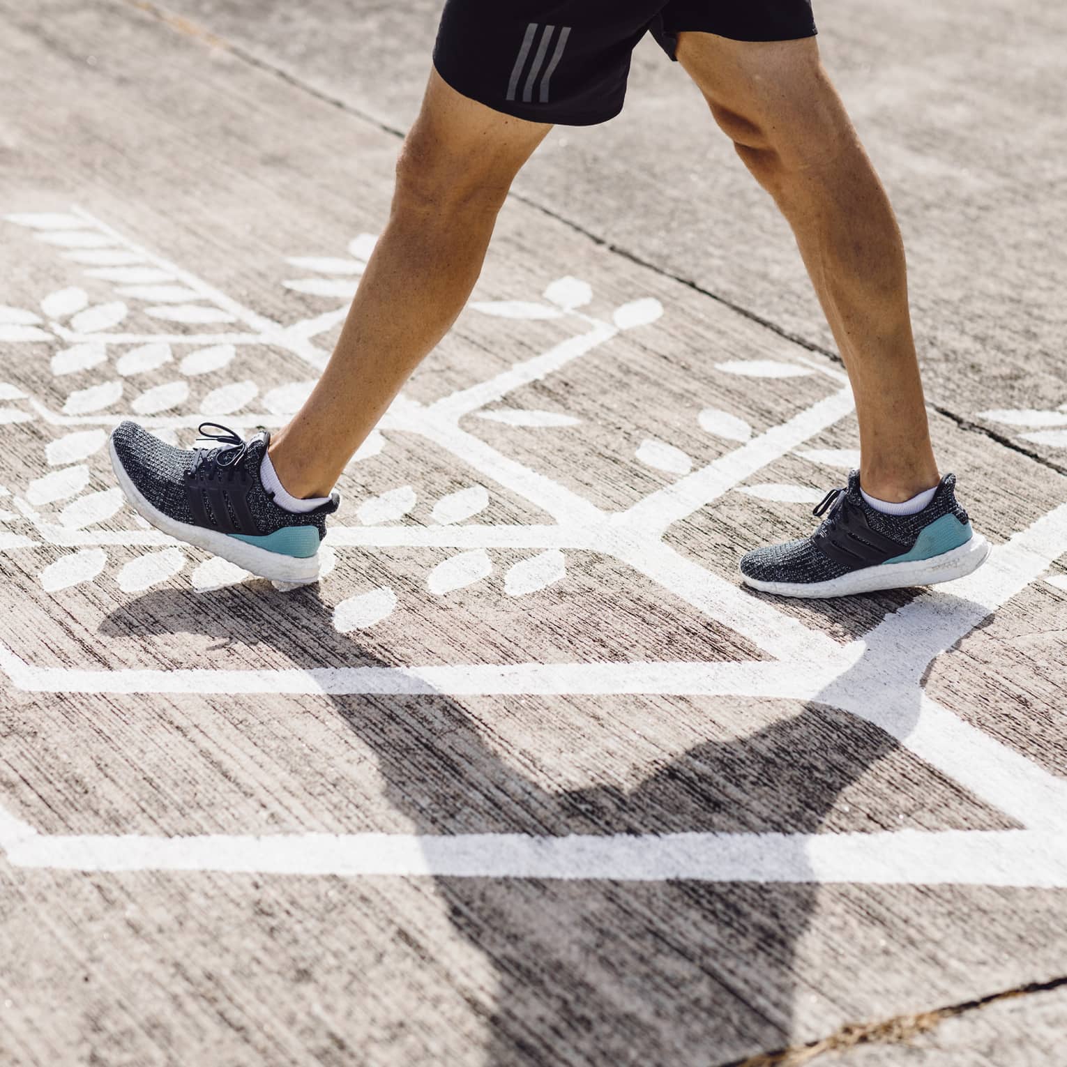 Man in navy blue trainers walks across Four Seasons logo on runway