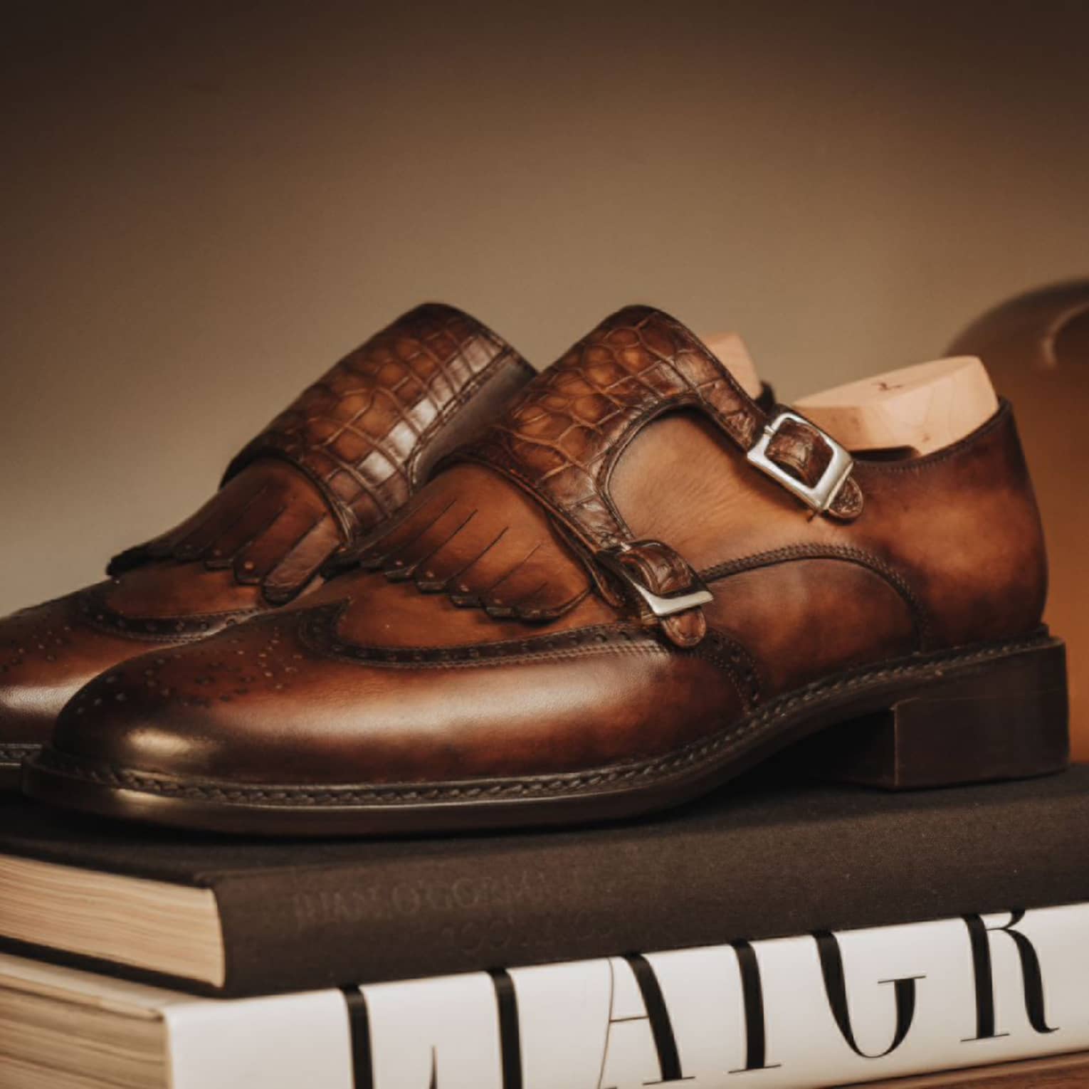 Brown leather shoes with silver buckles placed on top of two books.