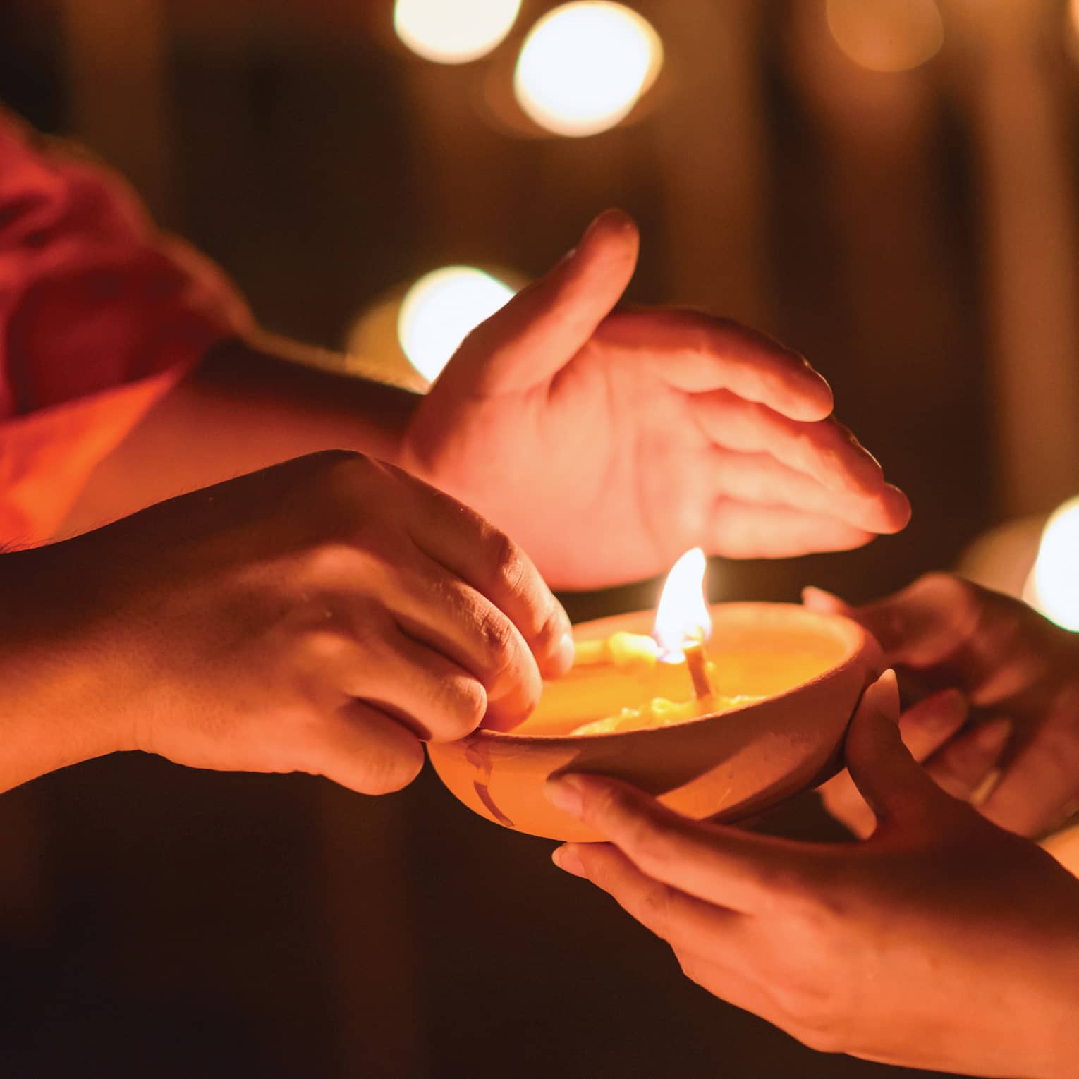 Buddhist monk hands holding candle cup in dark