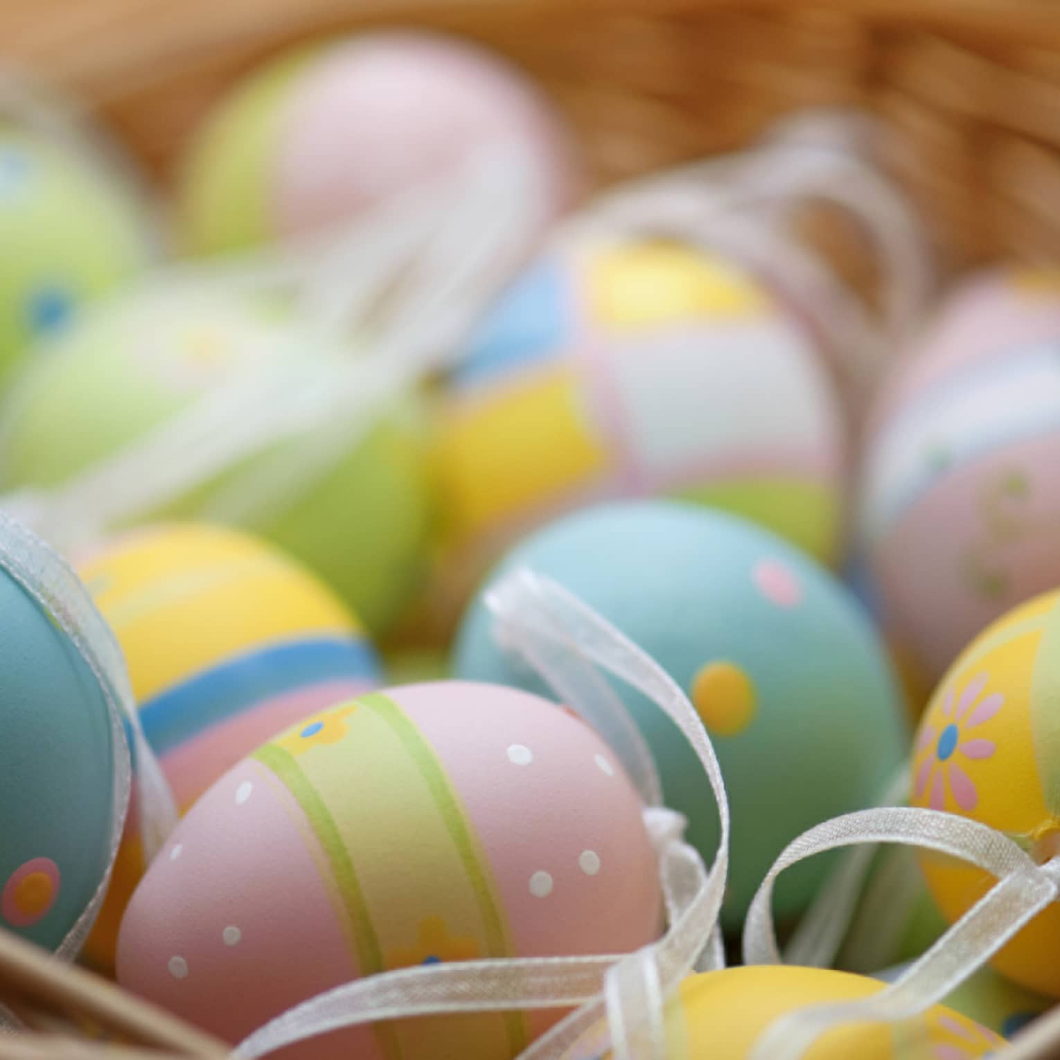 A basket of blue, pink, green and yellow colourful Easter eggs.
