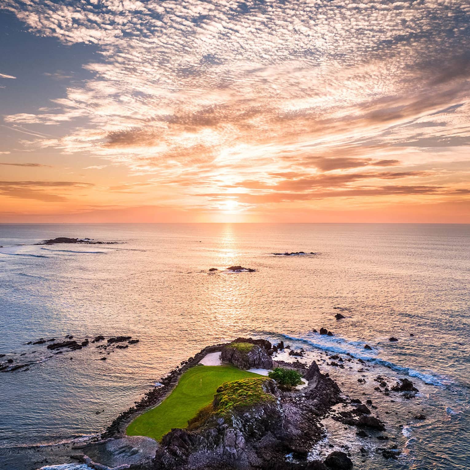 A small island that is part of a gold course, the sun is rising in the distance.