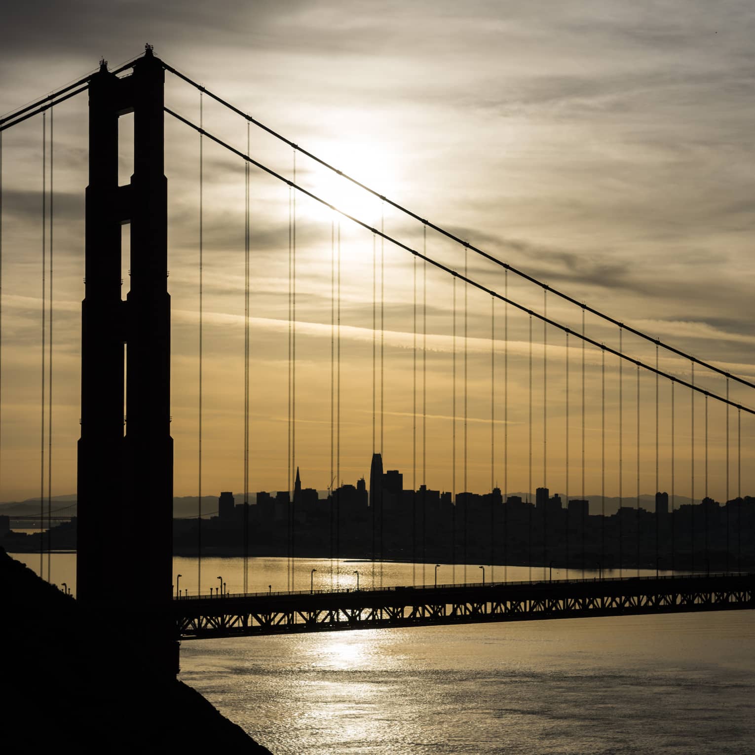 A metal bridge with the sun rising behind it.