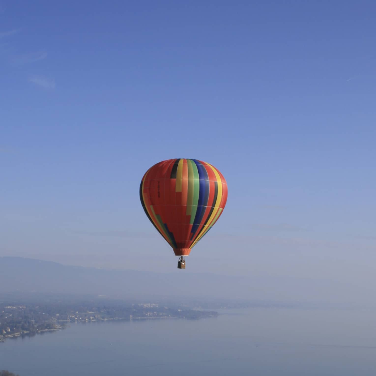 Colourful striped hot air balloon floating over Lake Geneva