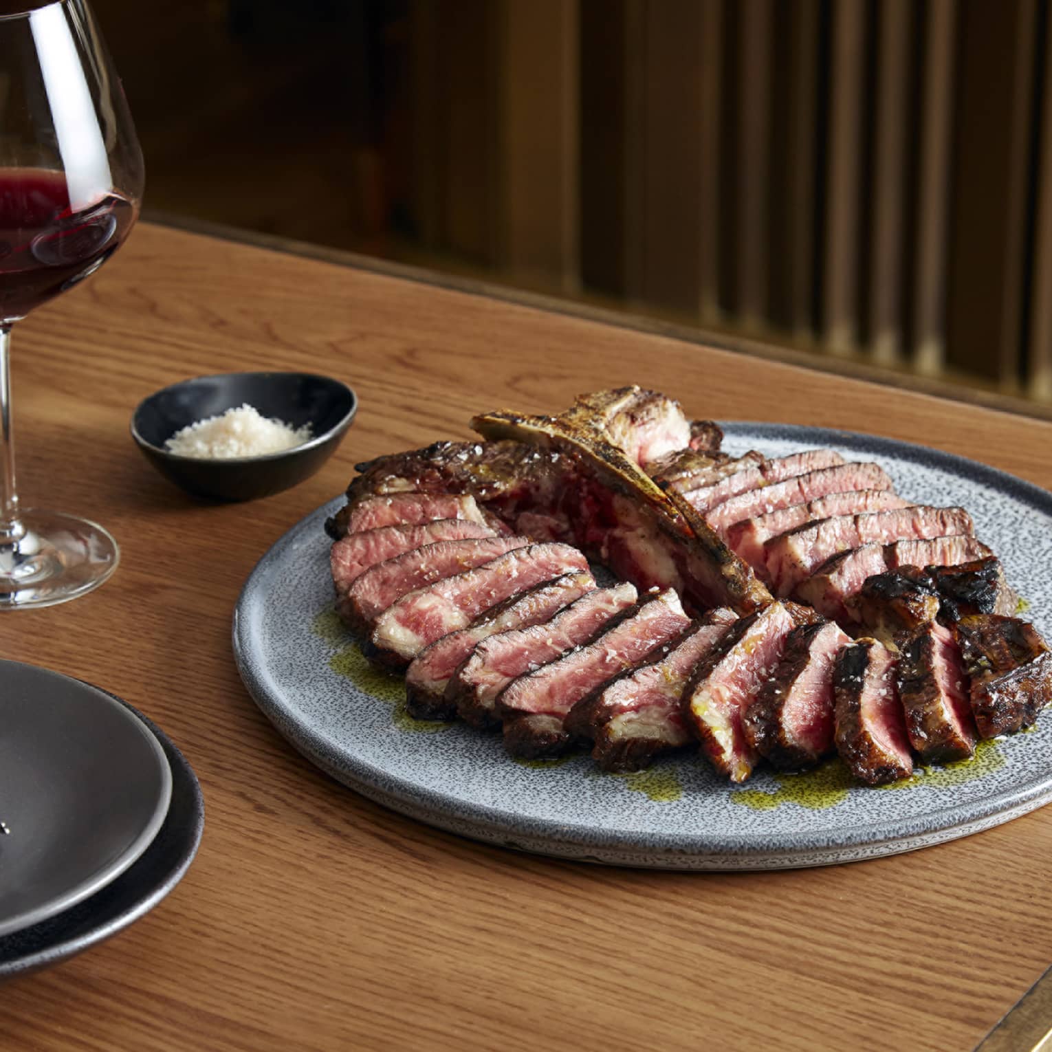 Slices of Dry-Aged T-Bone Steak arranged in circle on blue plate