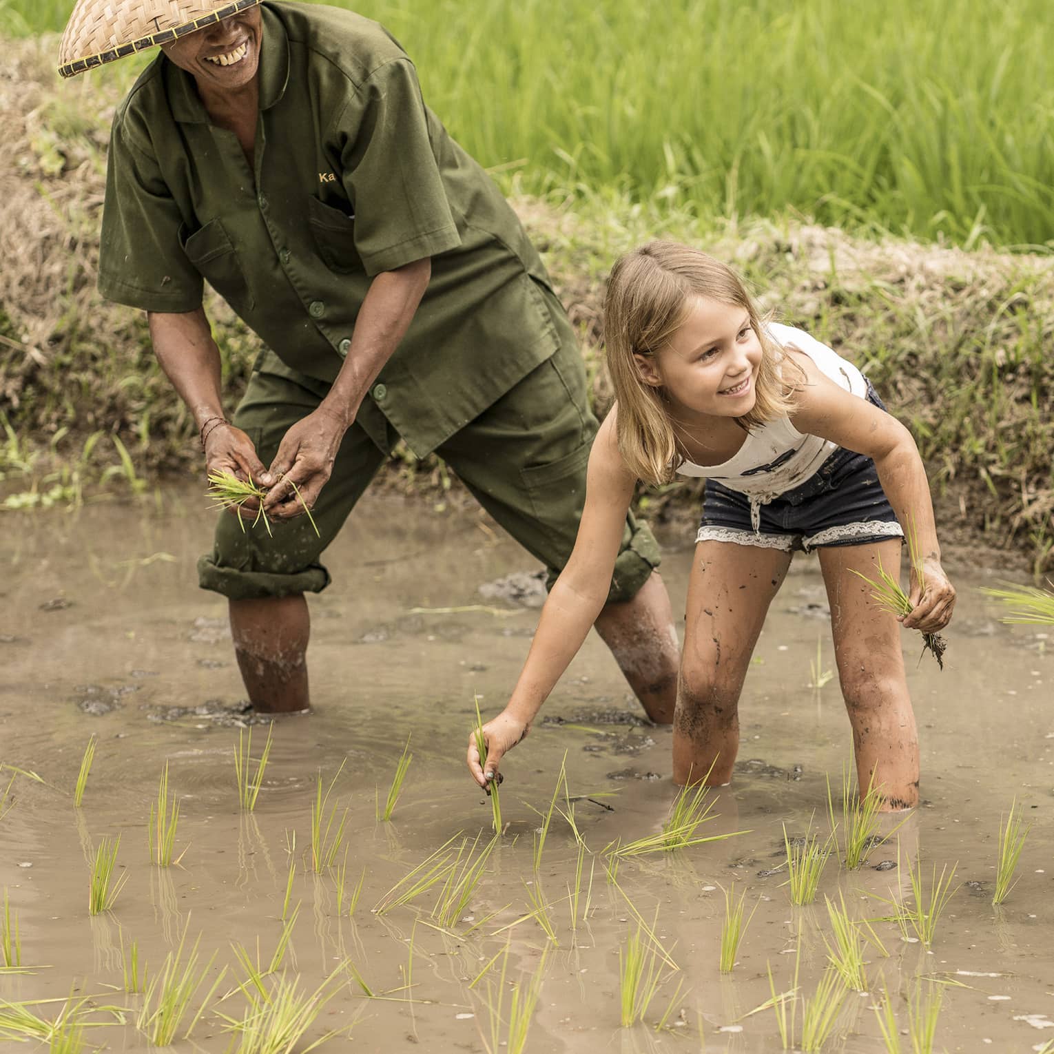 Four Seasons guests work in a rice field alongside a balinese farmer