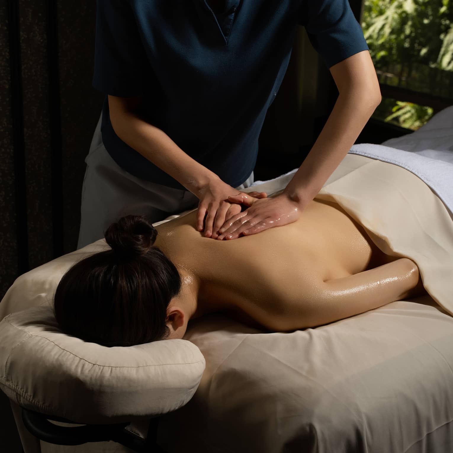 Person lying face down and covered in a beige sheet getting a massage