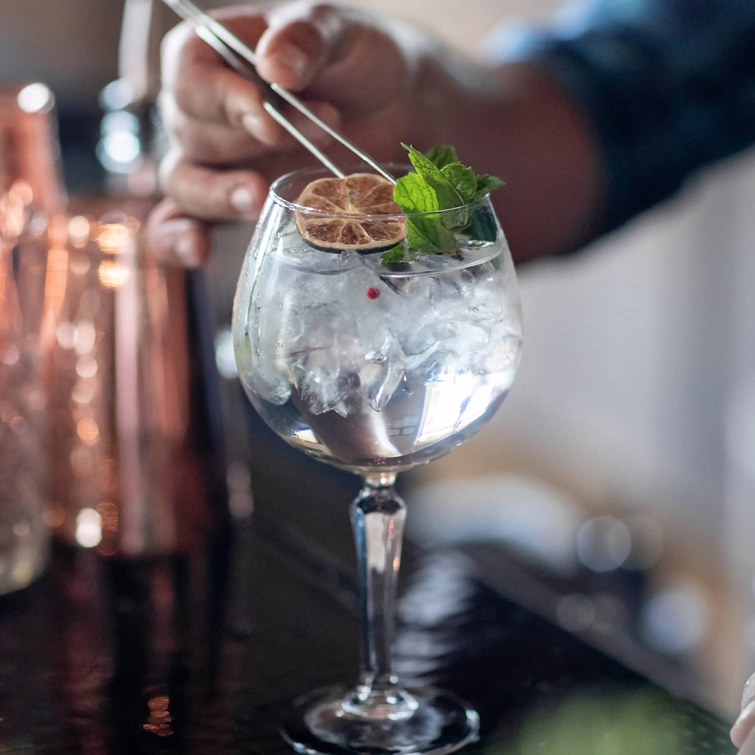 A clear cocktail with an orange wheel and herbs.