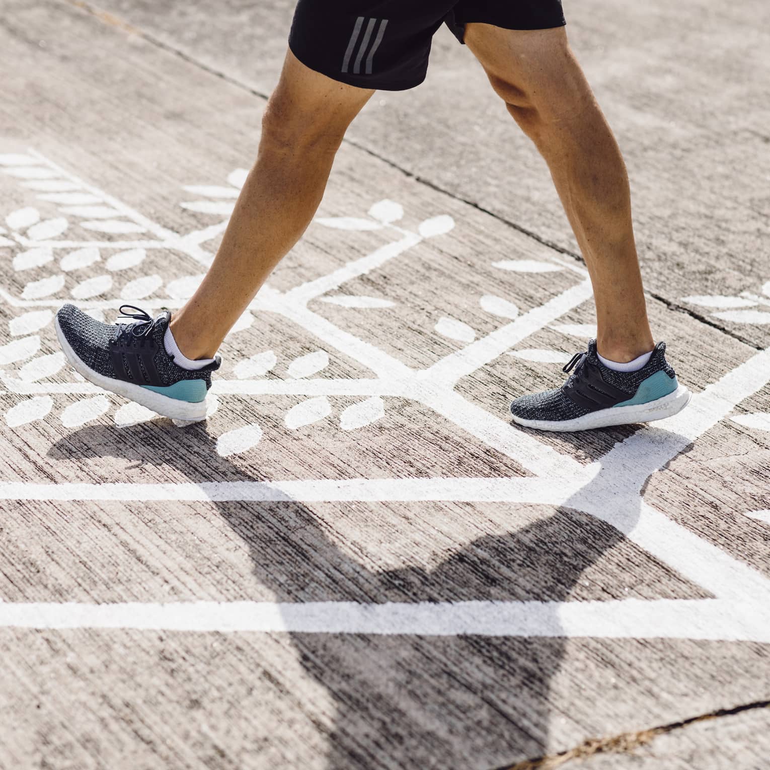 Man in navy blue trainers walks across Four Seasons logo on runway