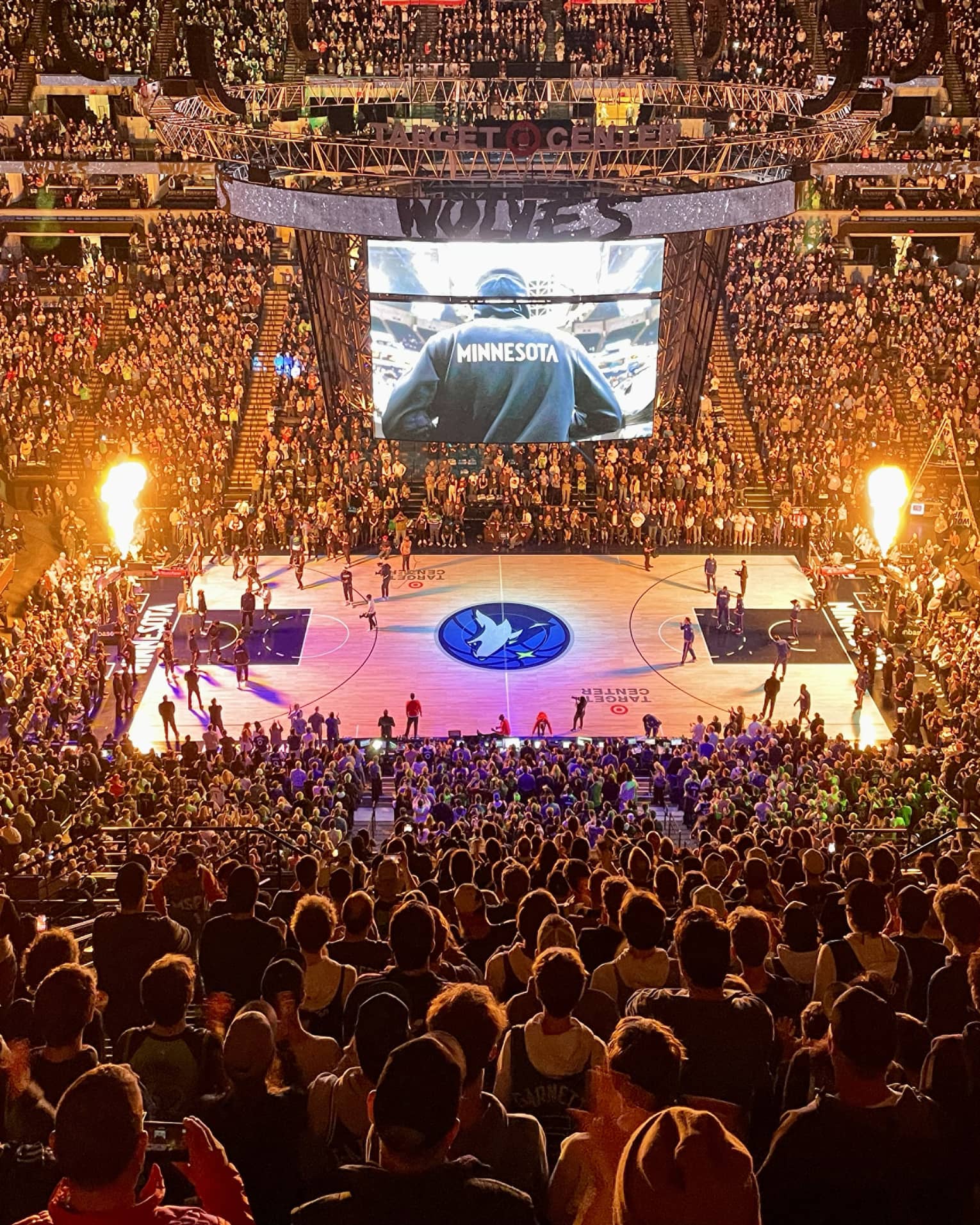 Large audience watching a basketball game with purple lights on the basketball court.
