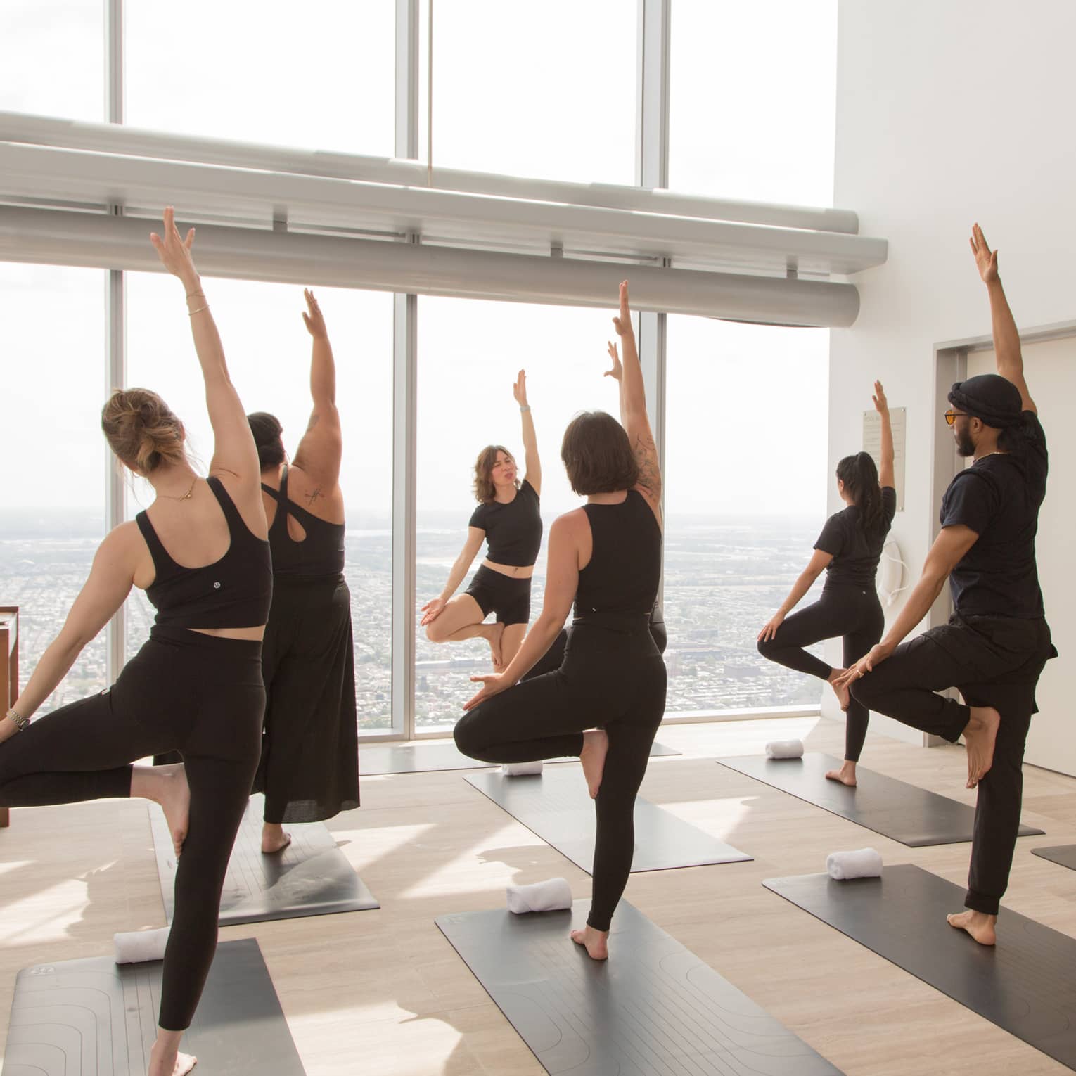 Guests taking a yoga class in a room with floor-to-ceiling windows