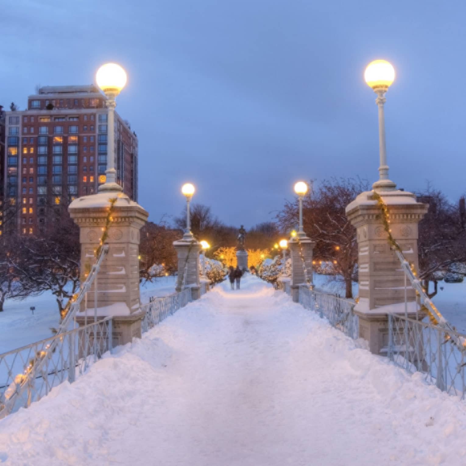 Bridge at night time covered in snow with city buildings in the background