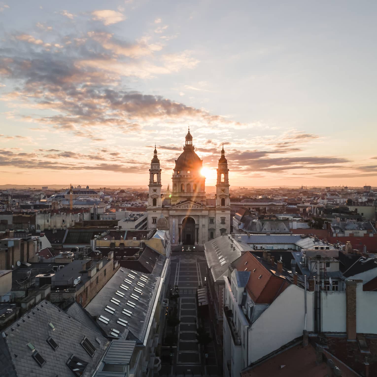 Historic domed cathedral with twin towers at sunrise above city rooftops