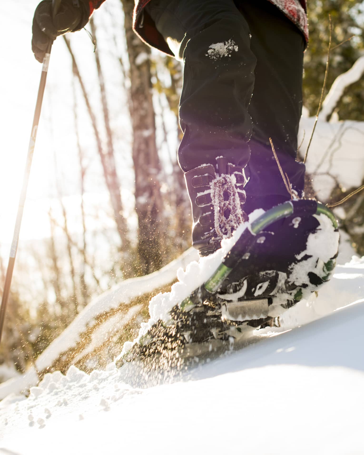 A person walking on snow using snow shoes and poles to help them walk.