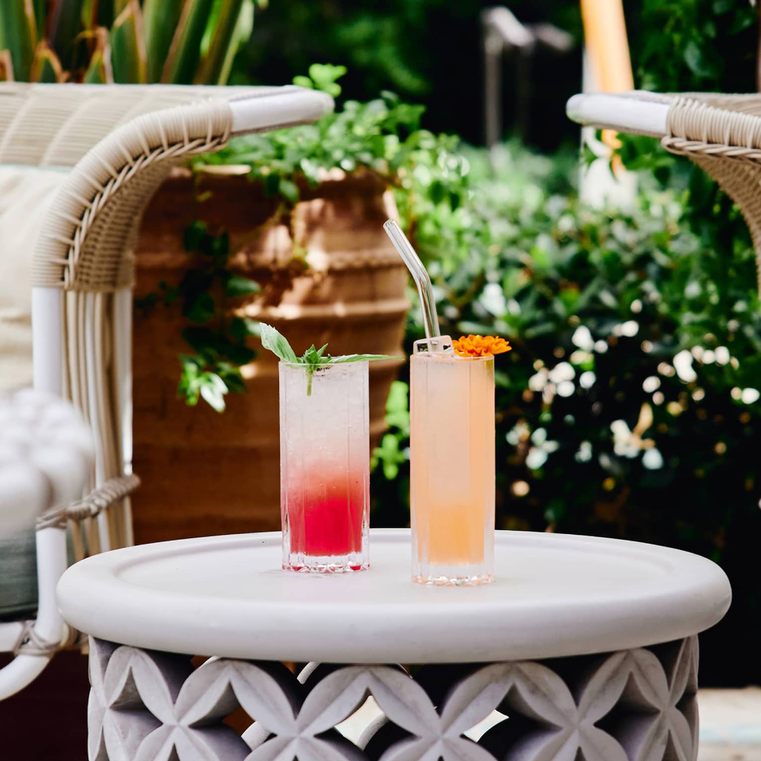 A red and orange cocktail on a small table outside.