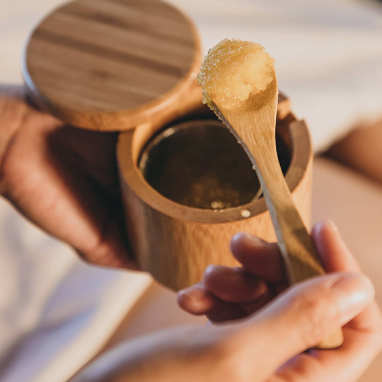 A spa staff member scoops some sugar scrub out of a bamboo container in Hawaii