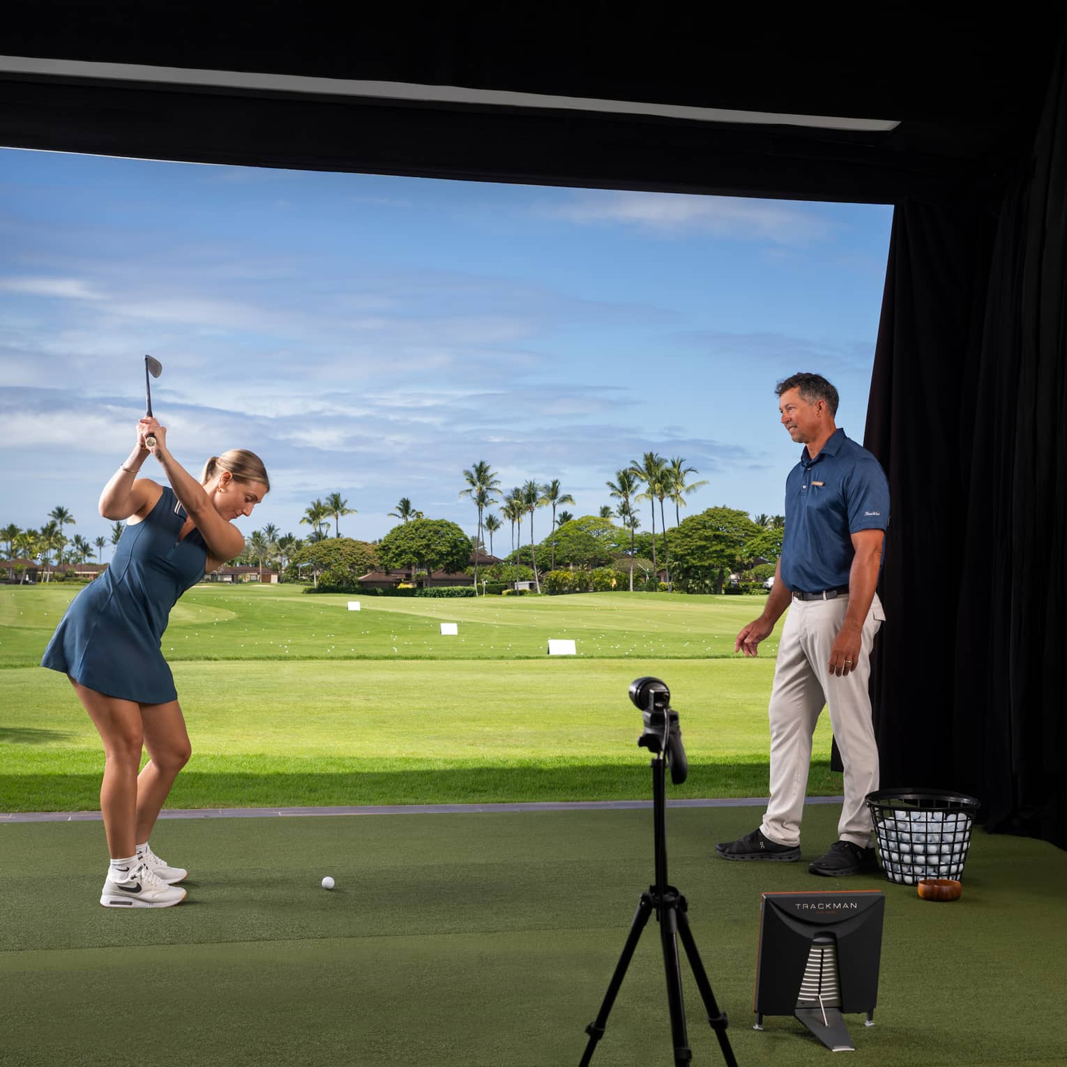 A woman practices her golf swing in an indoor simulator setting.