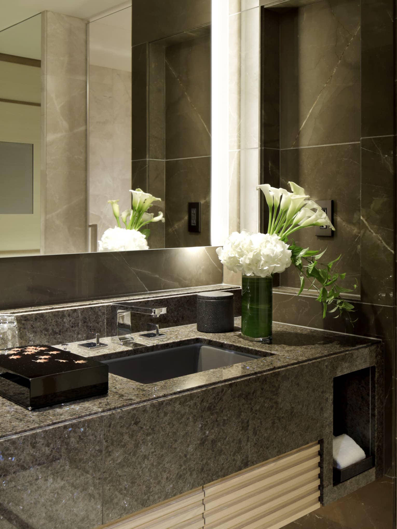 Luxury hotel bathroom with double sinks, marble countertops and fresh white flowers
