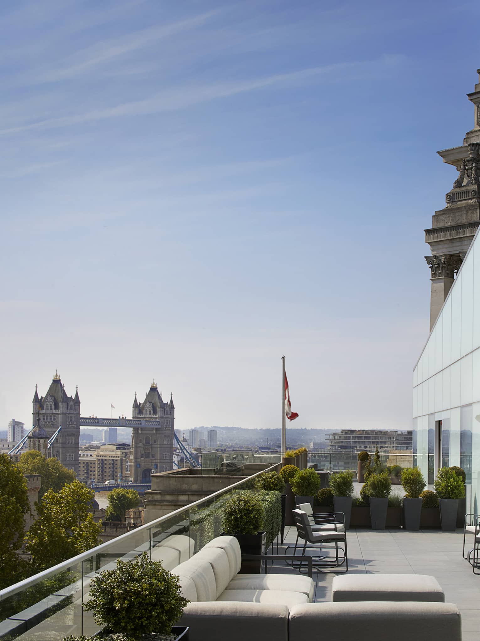 Patio with white sofas under modern two-storey glass wall