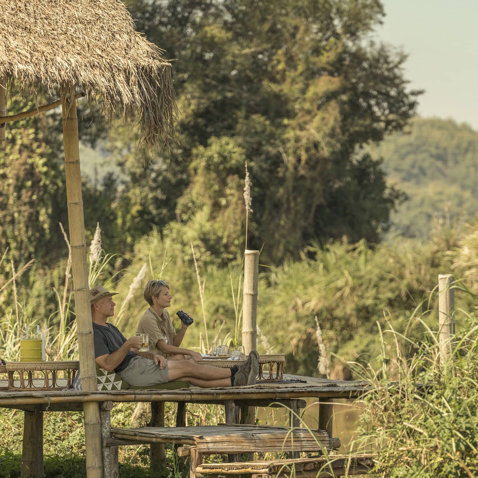 Couple enjoys a camp picnic with views of Thailand's rolling green hills